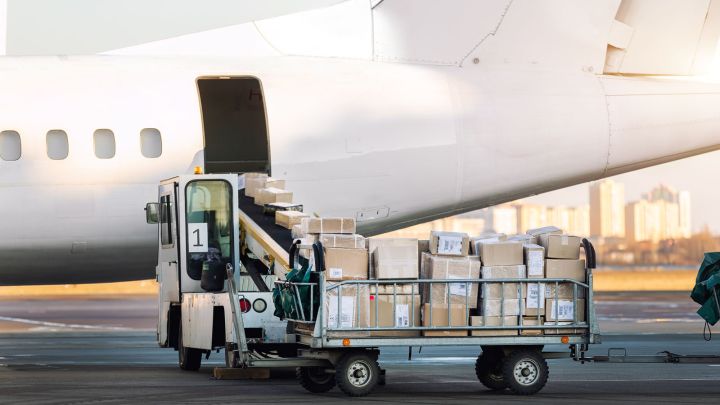 A cargo loader moves boxes to an airplane at an airport, ready for loading into the aircraft.